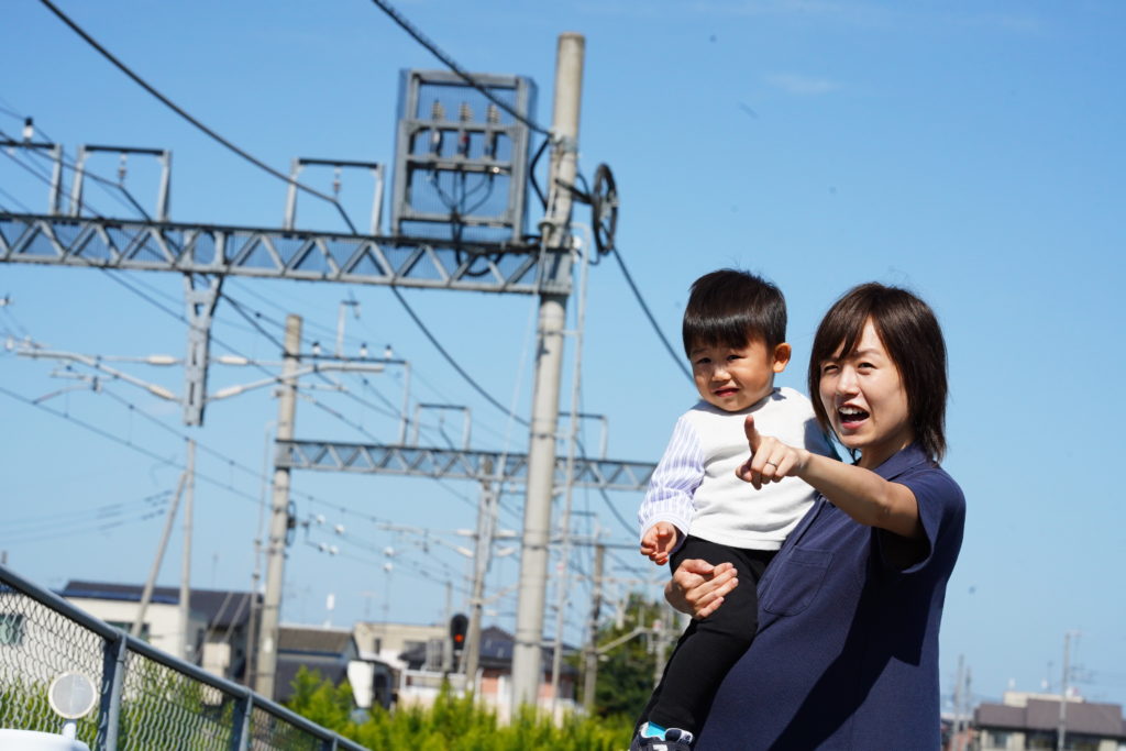 電車を通り過ぎるのを見る親子