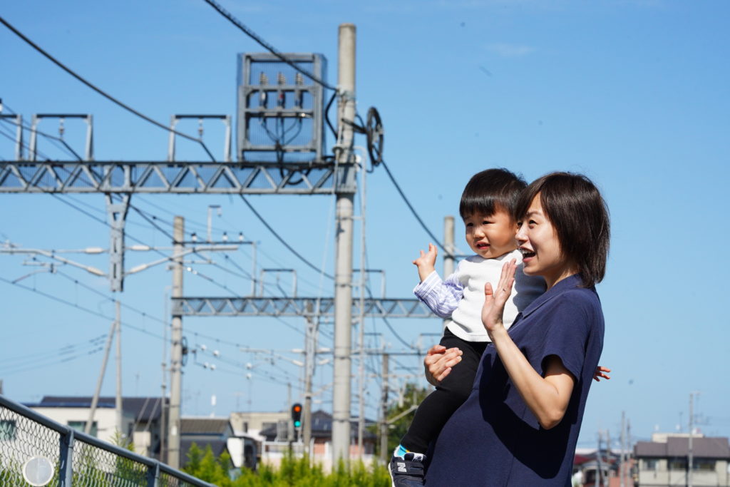 電車を通り過ぎるのを見る親子