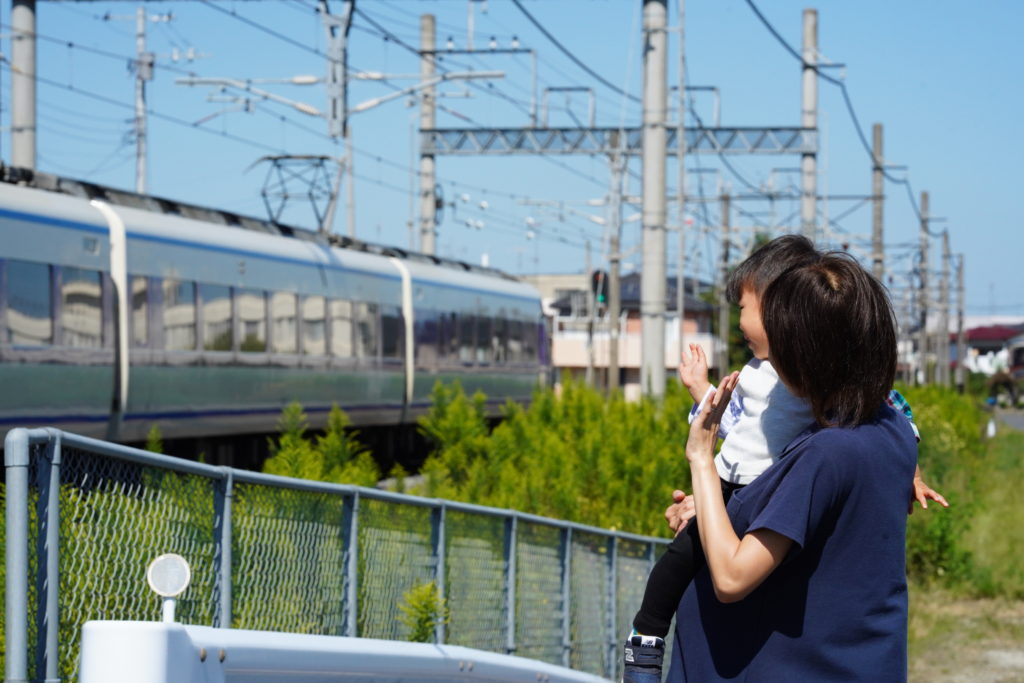 電車を通り過ぎるのを見る親子