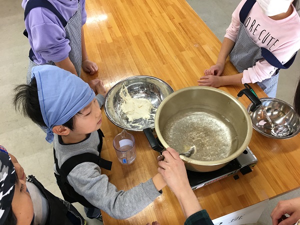 団子の生地を鍋の中へ落とす小学生