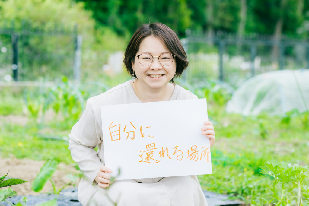 宮代町は自分に還れる場所　というボードを持つ長谷川さん