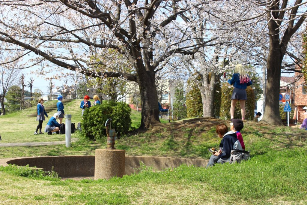 進修館の芝生広場『四季の丘』で、コスプレ撮影する人々と、井戸端でくつろぐ人々の様子
